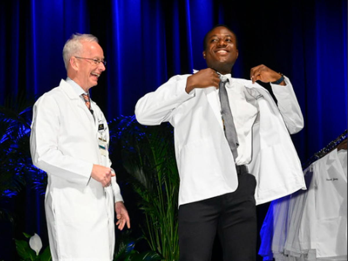 A student smiles after donning his white coat.