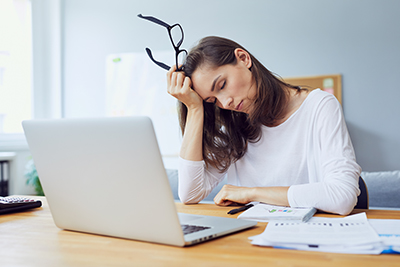 Gorgeous tired young office worker falling asleep at her desk while trying to work in modern office