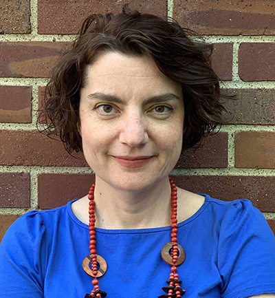 Headshot of Marija Žanić. She is wearing a blue top with a red-beaded necklace that has circular ornaments.