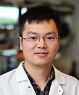 Headshot of Fubiao Shi wearing a lab coat and spectacles.
