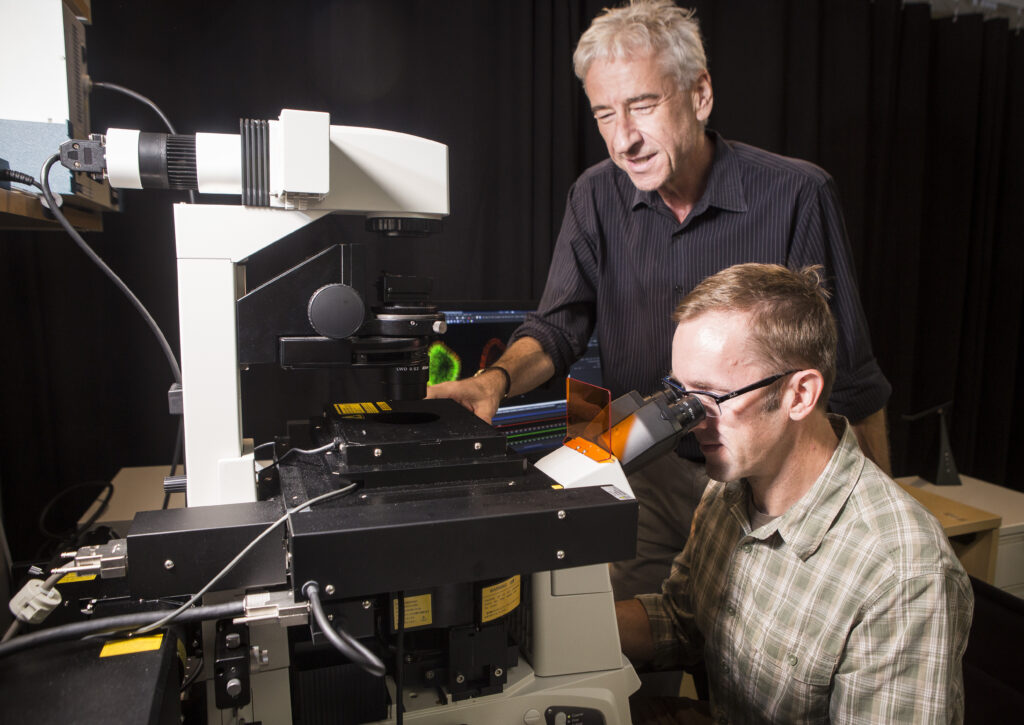 Matt Tyska at a large microscope with Ian Macara looking over his shoulder.