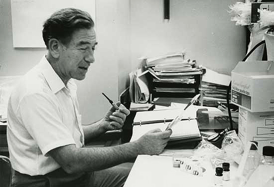 Stanley Cohen in his research lab, holding a pipe.
