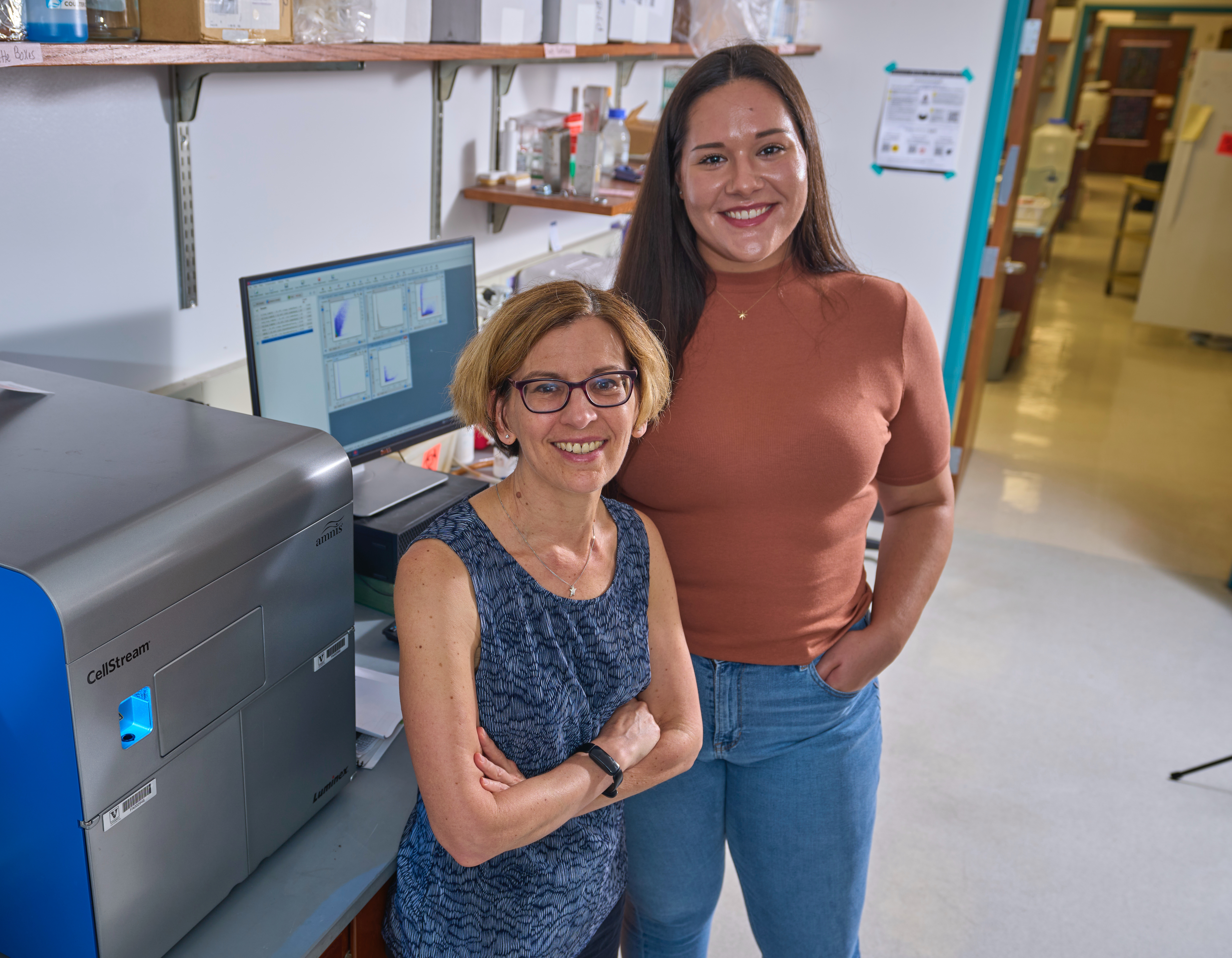 Alissa Weaver and Ariana von Lersner standing in front of a piece of lab equipment and a computer.