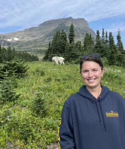 Photo of Mary Gray Lindstrom with mountain goat and mountain scene in the background.