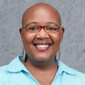 Headshot of Felysha Jenkins. She is bald and is wearing long earrings and a light-blue collared shirt.