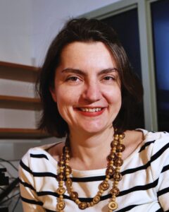 Headshot of Marija Zanic. She is wearing a white top with thin, black stripes and a wooden necklace.
