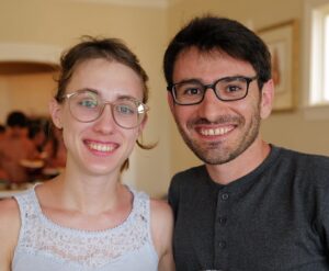 Two people. Hossein Jashnsaz, wearing glasses and a black or dark gray buttoned top, is on the right. On the left is a woman who is wearing glasses and a baby blue tank top.