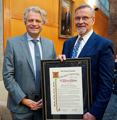 Daniel Diermeier (left) and Barney Graham (right). Graham is holding his framed Distinguished Alumni Award, which is stylized like a medieval letter (with stylish letters and colorful touches down the left side of the letter).