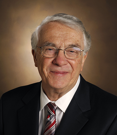 Headshot of Professor Michael Waterman wearing a dark blazer, red striped tie, and eyeglasses.