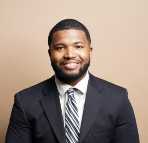 A bearded man in a suit and tie smiles