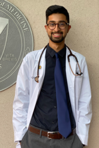 A man in a white coat and stethoscope smiles