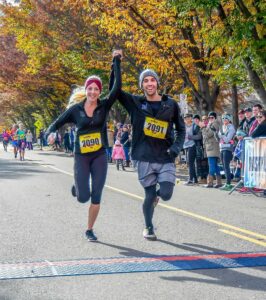 Two runners clasp hands as they cross the finish line