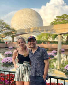 A couple poses in front of the iconic sphere at Epcot, Walt Disney World