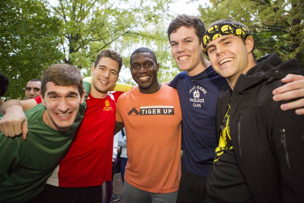 Five men wrap arms around each other for a photo