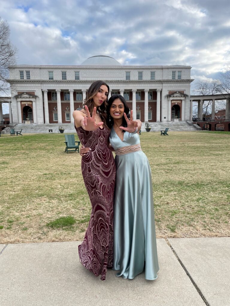 Two women in black tie dresses pose