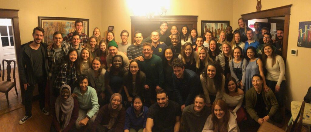 A large group of students gather in a living room