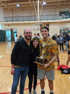 Two men and a woman stand in a gym