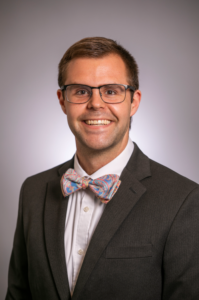 A man in a bowtie smiles for a headshot