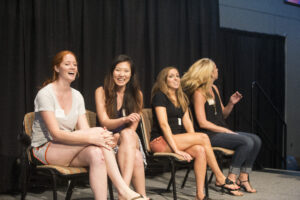 Four women sit on folding chairs