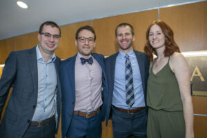 Three men and one woman pose for a photo