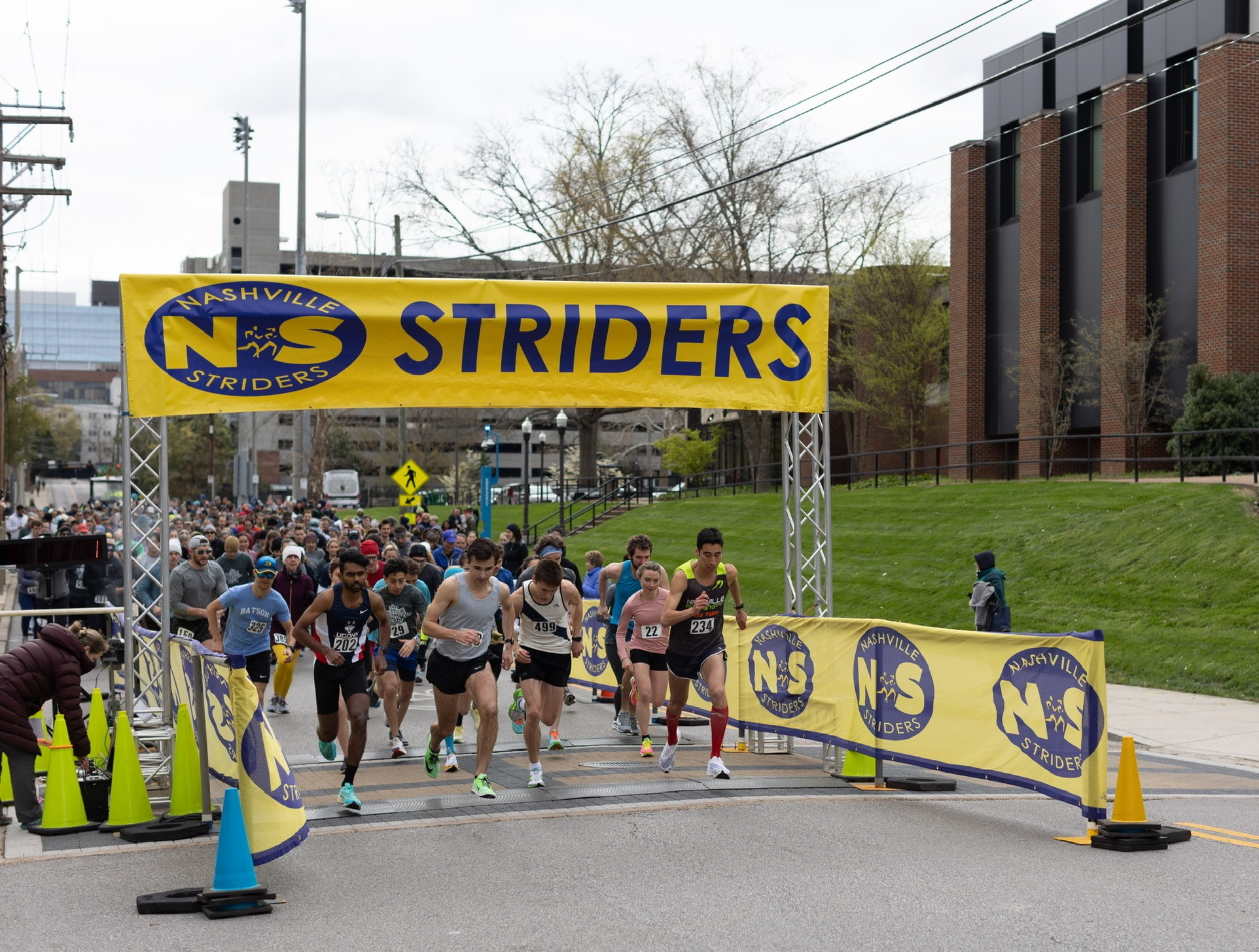 Runners cross the starting line below a Nashville Striders banner