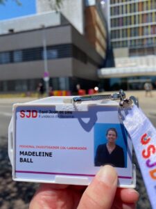 A hand holds a hospital badge with a photo of a woman