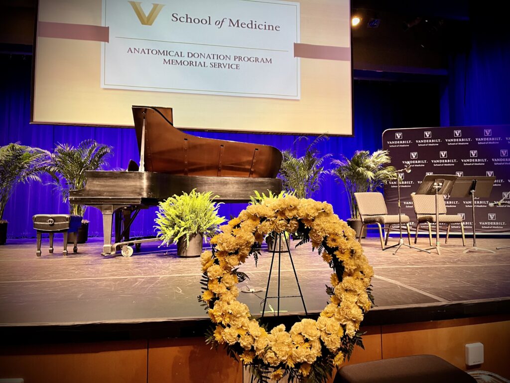 A lone wreath sits in front of a stage with a piano