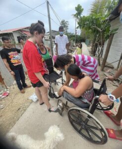 A family helps a girl out of an old wheelchair and into a new