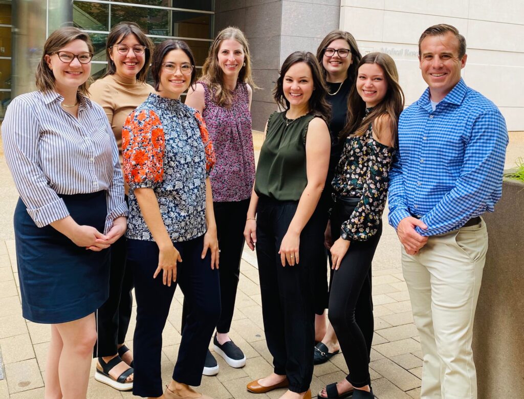 A group of genetic counseling students stand outside on a medical plaza
