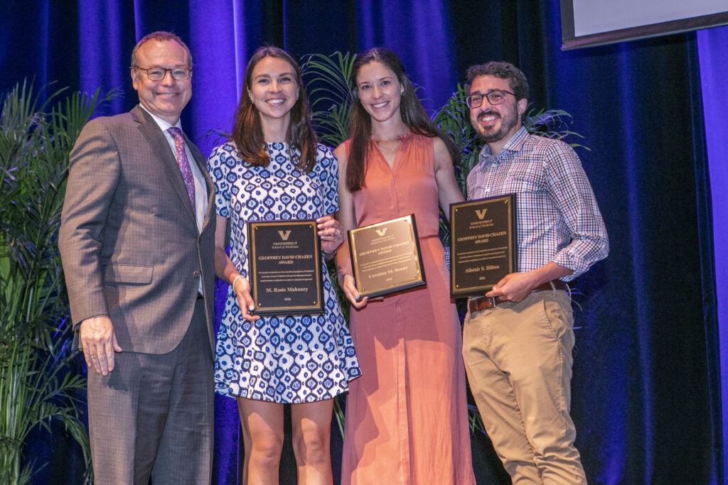 A dean stands with three award winners