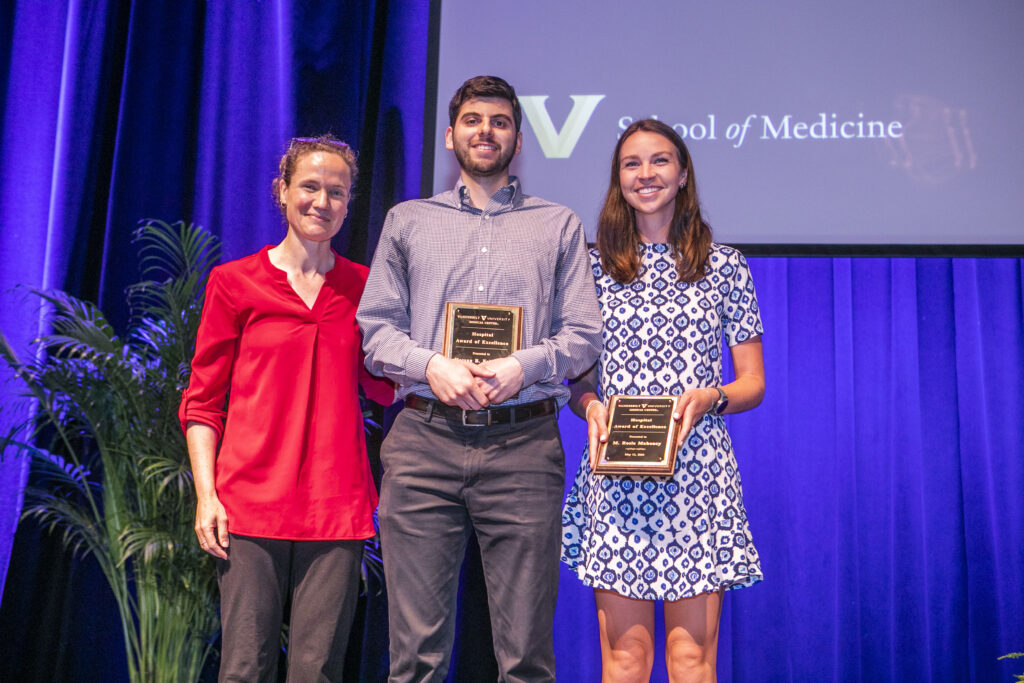 A surgeon stands with two award winners