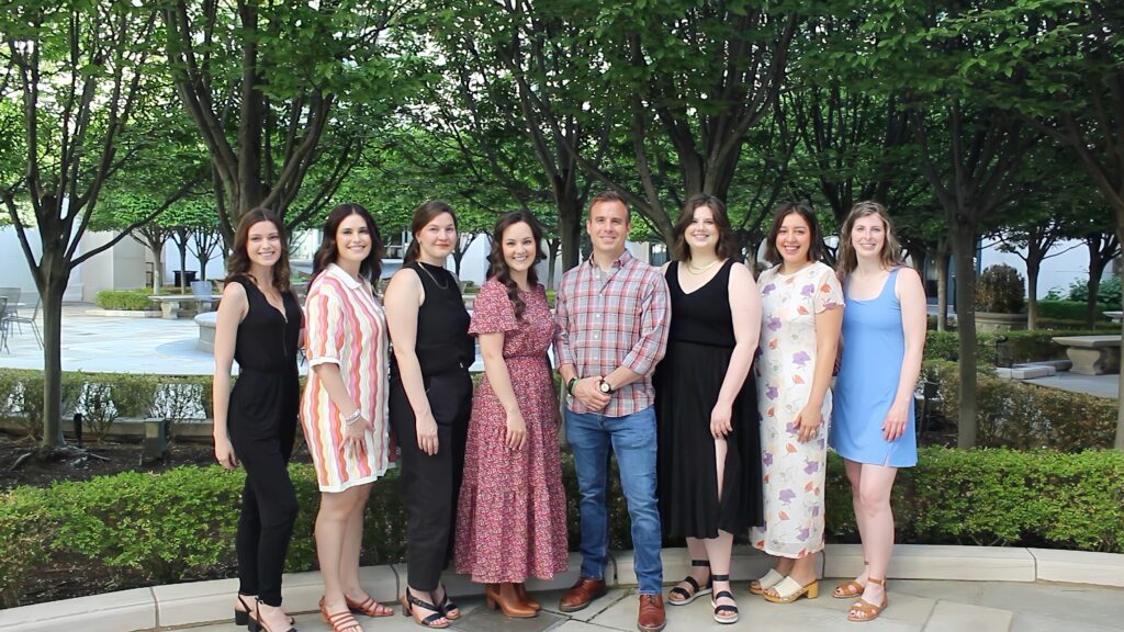 A group of genetic counselors stand outside in front of trees