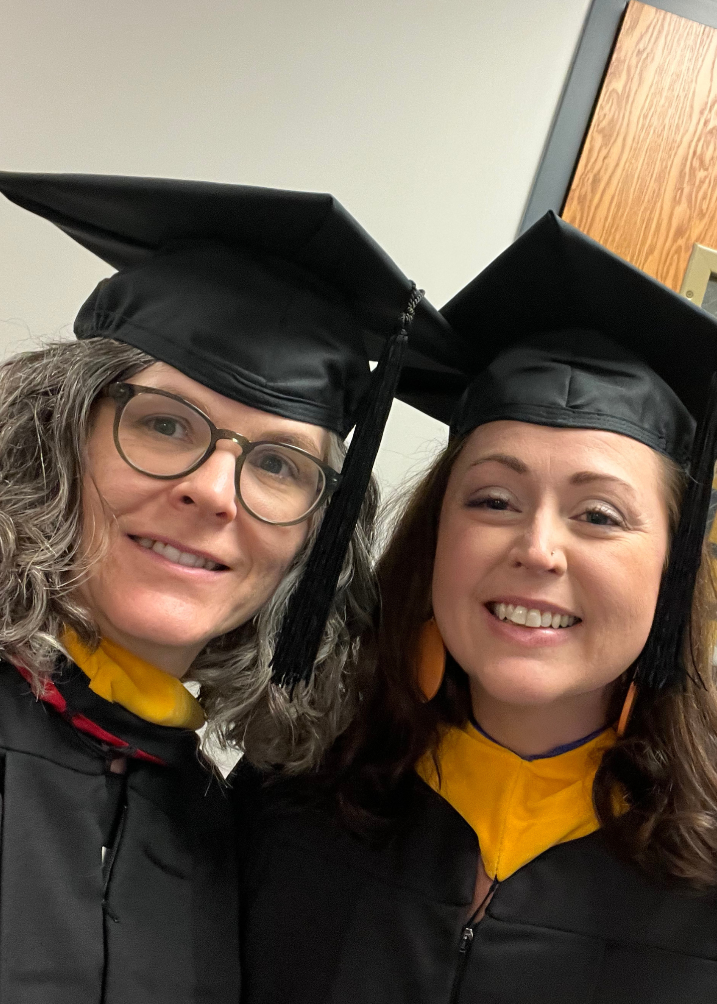 Two women in academic regalia smile