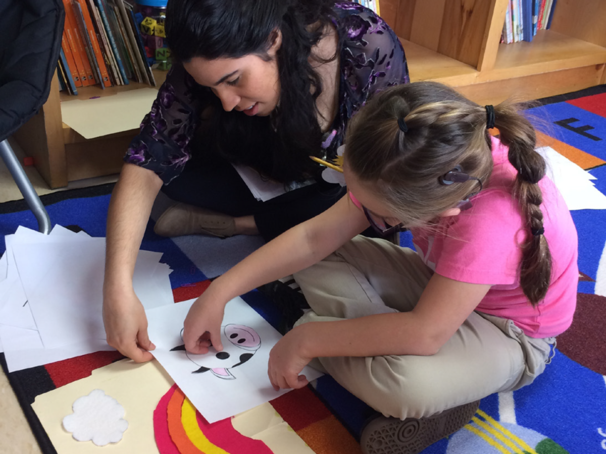 An MDE student works with a deaf child using pictures. 